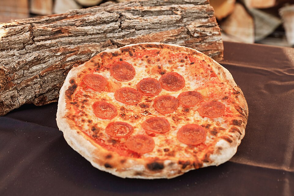 Pizza artesanal com manjericão diante do forno a lenha